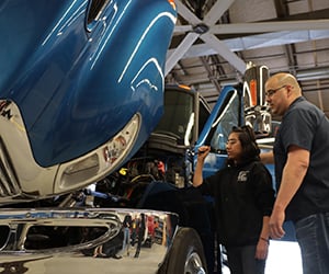 Diesel and Transportation Technology Program Students and Instructor looking over a truck engine